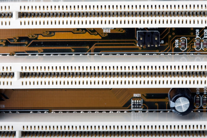 Close-up of section of a computer motherboard showing rows of PCI slots. These are used for expansion cards, such as graphics, sound and accelerator cards for data input and output. No trademarks / logos.