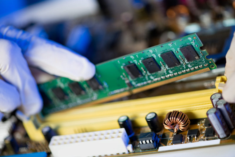 Cropped image of an electronic engineer putting RAM into the memory slot on motherboard