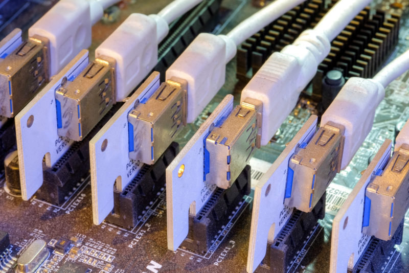 Close-up and selective focus a row of Riser card and USB 3.0 that installed on PCI-E slot of motherboard to connected multi-graphics card for work on PC Bitcoin miner